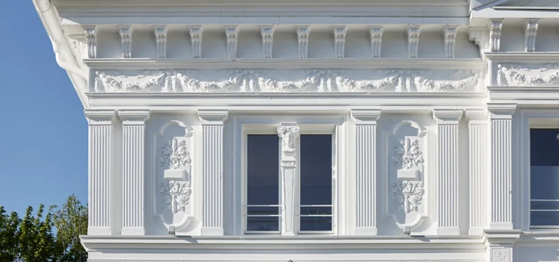 Fassaden-Detail des Rubedo Spa — ionische Säule und Blumenreliefs an der Stuckfassade