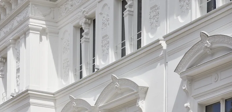Stuck-Detail an der Fassade des Rubedo Spa — Blumen-Reliefs und Kannelur-Pilaster